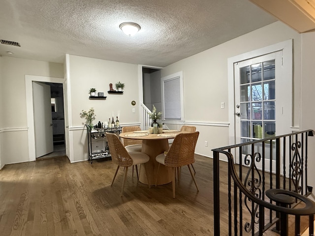 dining space featuring a textured ceiling, dark wood-style flooring, and visible vents