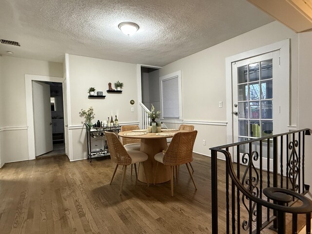 dining room featuring dark wood-type flooring, a textured ceiling, and visible vents