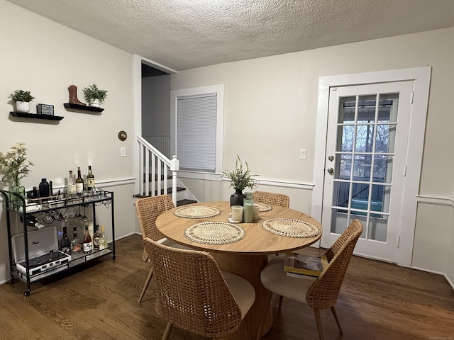 dining room featuring a textured ceiling, stairway, and wood finished floors