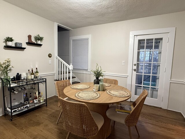dining area with stairway, a textured ceiling, and wood finished floors