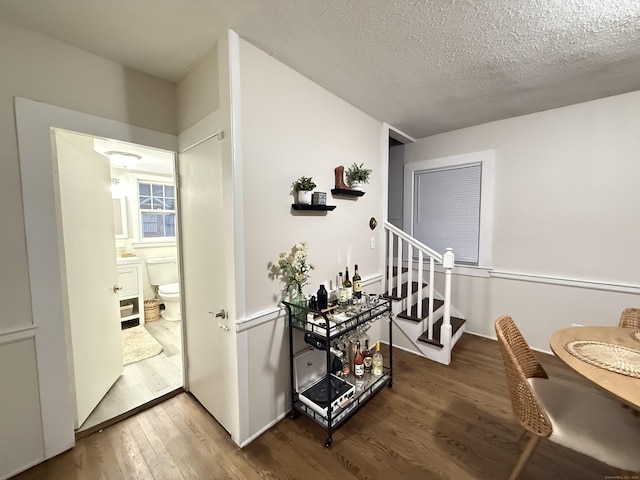 corridor with wood-type flooring, stairway, and a textured ceiling