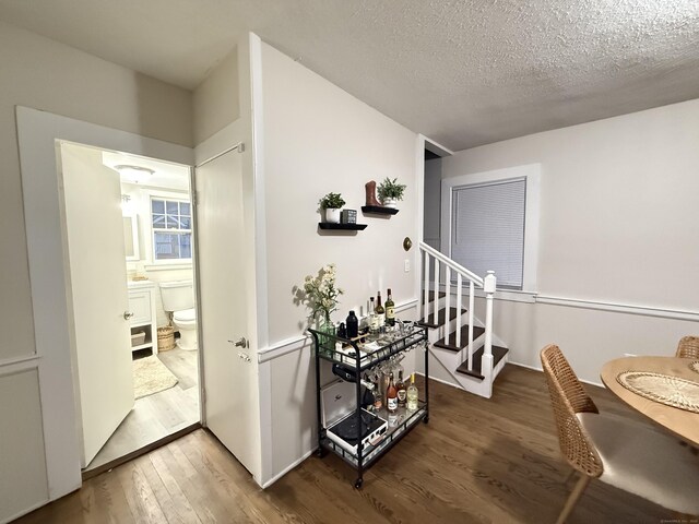 hallway featuring a textured ceiling, wood finished floors, and stairway