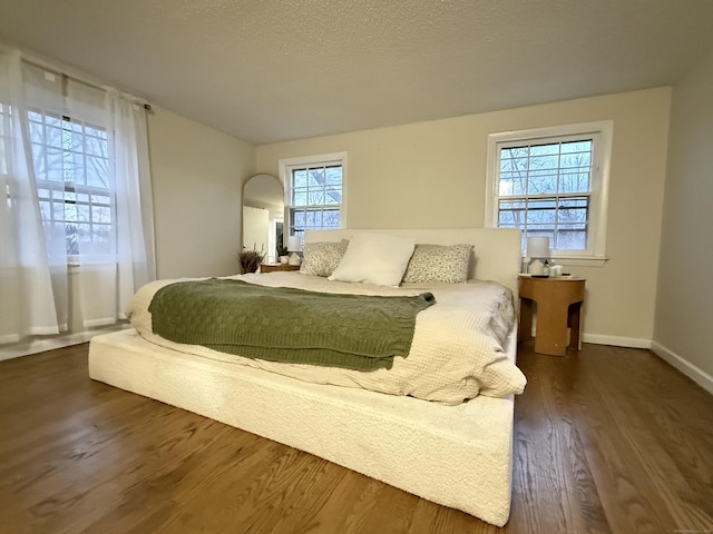 bedroom featuring dark wood-style floors, a textured ceiling, and baseboards