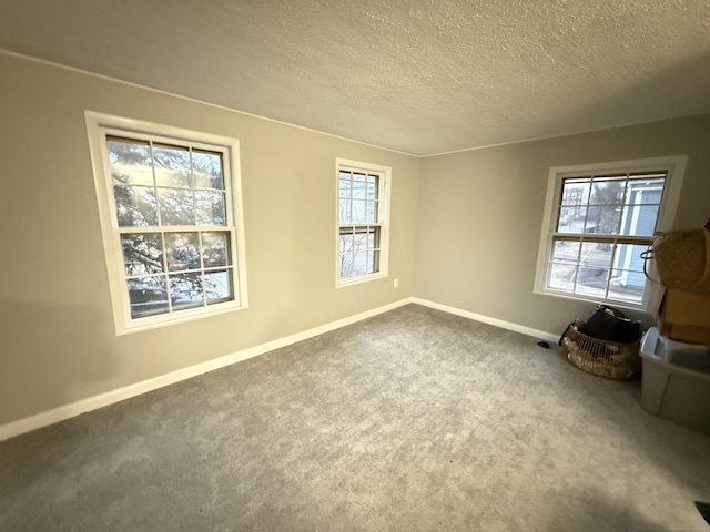 unfurnished room featuring a textured ceiling, carpet flooring, and baseboards