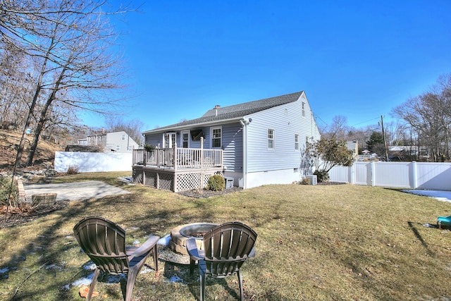 rear view of property featuring an outdoor fire pit, a lawn, a fenced backyard, a chimney, and a wooden deck