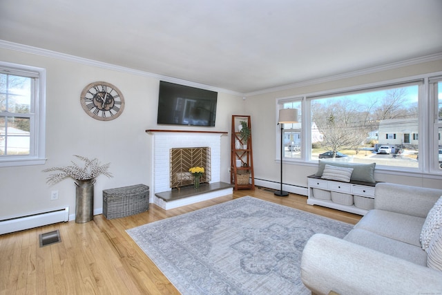 living area with a brick fireplace, wood finished floors, visible vents, and a healthy amount of sunlight