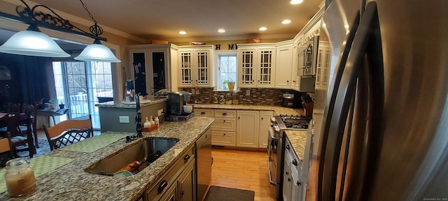 kitchen with stainless steel appliances, a healthy amount of sunlight, decorative backsplash, glass insert cabinets, and crown molding