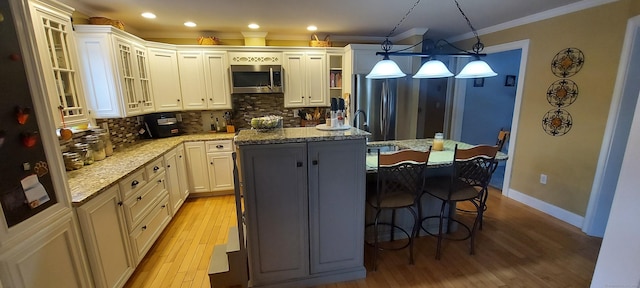 kitchen featuring tasteful backsplash, a center island with sink, appliances with stainless steel finishes, and ornamental molding