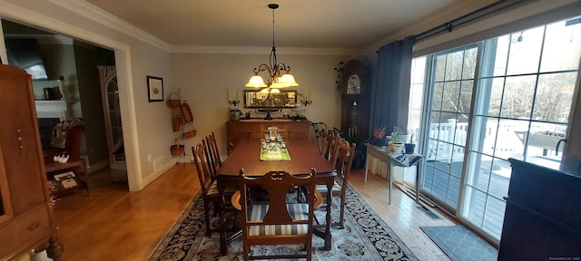 dining area with an inviting chandelier, ornamental molding, and light wood finished floors