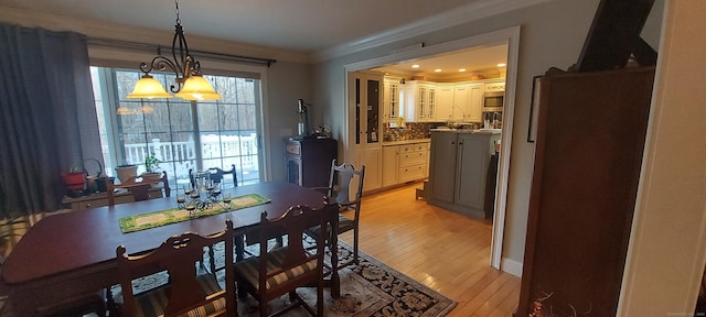 dining space featuring light wood finished floors and crown molding