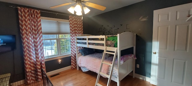 bedroom with visible vents, baseboards, ceiling fan, and wood finished floors