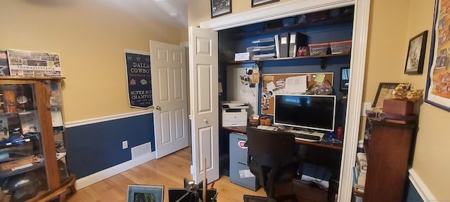 office space with baseboards, visible vents, and wood finished floors