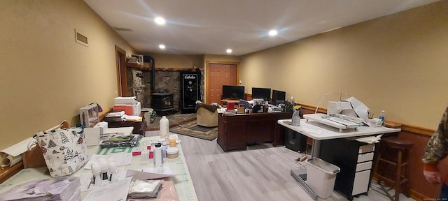 home office with recessed lighting, a wood stove, visible vents, and light wood finished floors