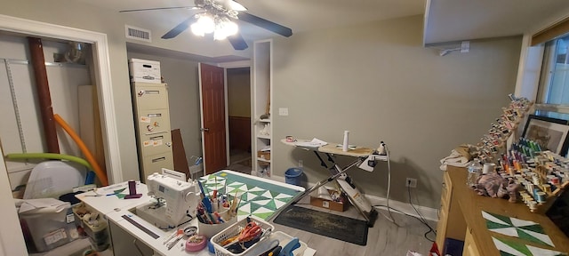 office area with a ceiling fan, wood finished floors, visible vents, and baseboards