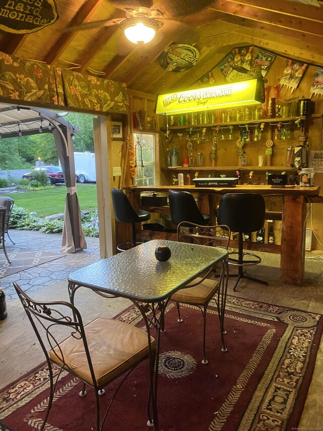 interior space with vaulted ceiling, a dry bar, and wood walls