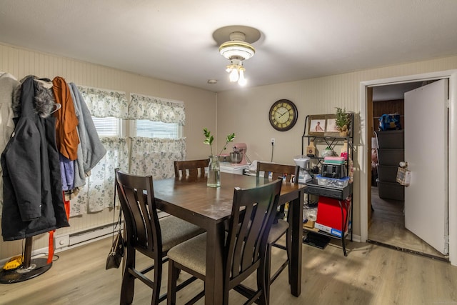 dining space with light wood finished floors and a baseboard heating unit