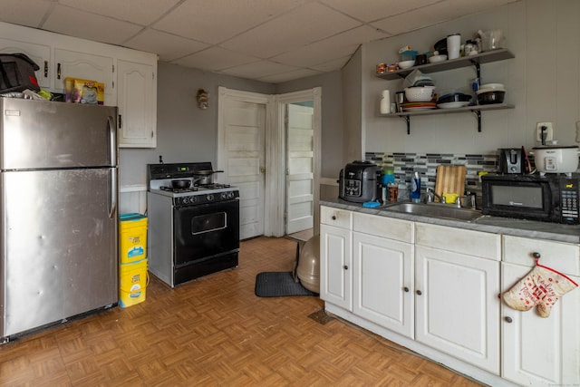 kitchen featuring a drop ceiling, backsplash, black appliances, white cabinetry, and a sink