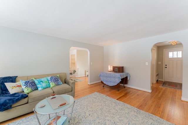 living room featuring baseboards, arched walkways, and wood finished floors