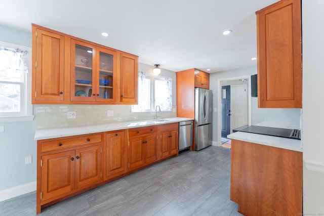 kitchen featuring glass insert cabinets, brown cabinetry, appliances with stainless steel finishes, and light countertops