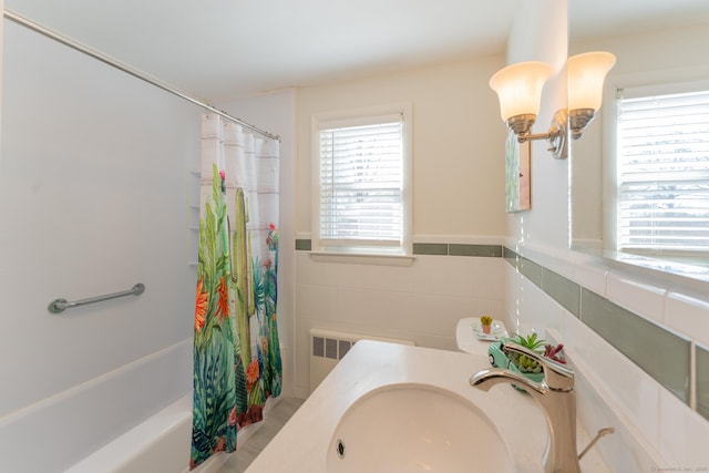 full bath with radiator heating unit, tile walls, a sink, and wainscoting