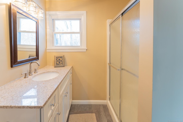 bathroom with a stall shower, baseboards, and vanity