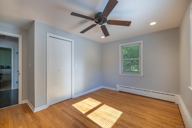 unfurnished bedroom featuring a baseboard radiator, recessed lighting, baseboards, and wood finished floors