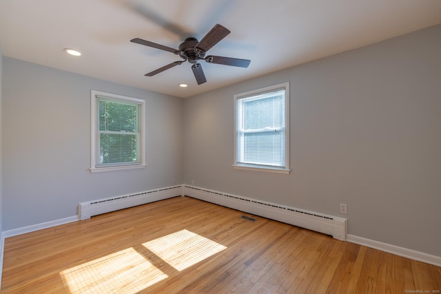 spare room with baseboards, a baseboard radiator, wood finished floors, and a healthy amount of sunlight