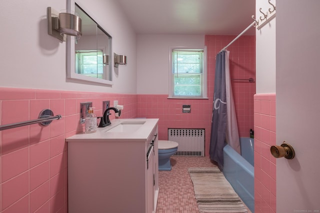 bathroom featuring toilet, tile walls, vanity, wainscoting, and radiator