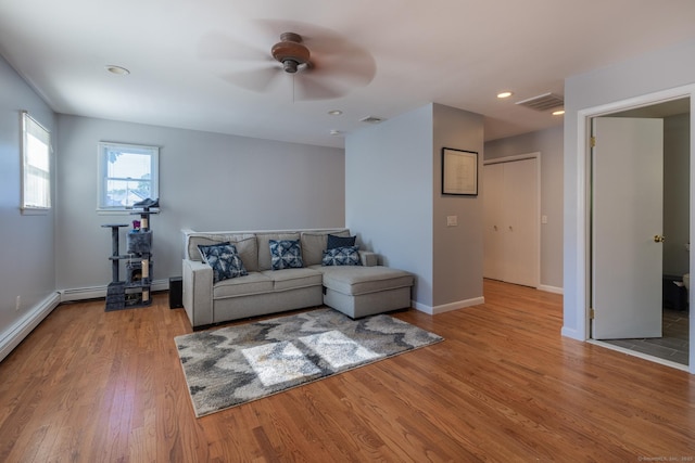 living area featuring baseboards, visible vents, ceiling fan, and wood finished floors