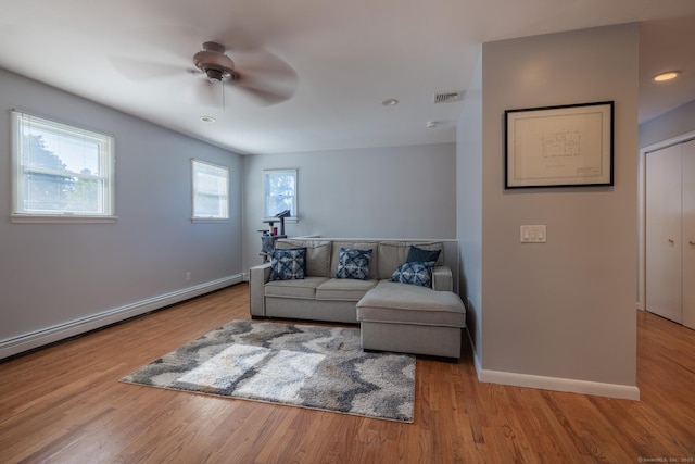 living room featuring baseboards, a baseboard radiator, visible vents, and wood finished floors