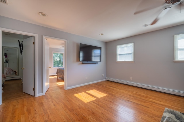 unfurnished bedroom featuring light wood-style floors, baseboards, a baseboard heating unit, and ceiling fan