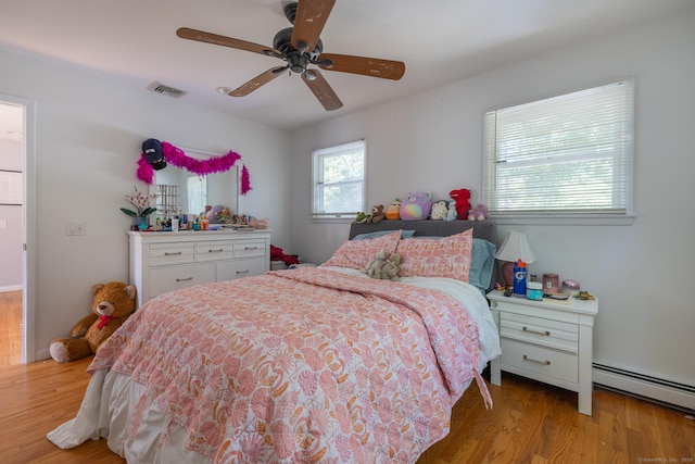 bedroom featuring a baseboard heating unit, light wood-type flooring, visible vents, and ceiling fan