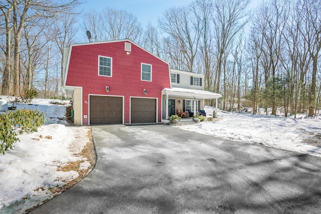 dutch colonial with covered porch, driveway, and an attached garage