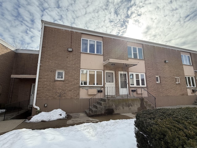 snow covered house featuring brick siding