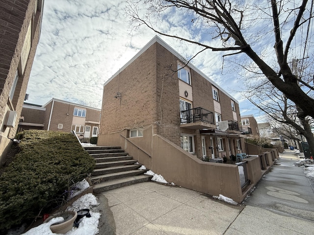 exterior space with a balcony, a fenced front yard, and brick siding