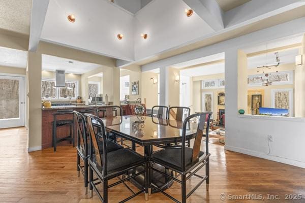 dining space with beamed ceiling, wood finished floors, and baseboards