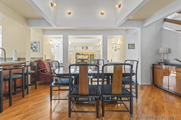 dining space featuring beamed ceiling and wood finished floors