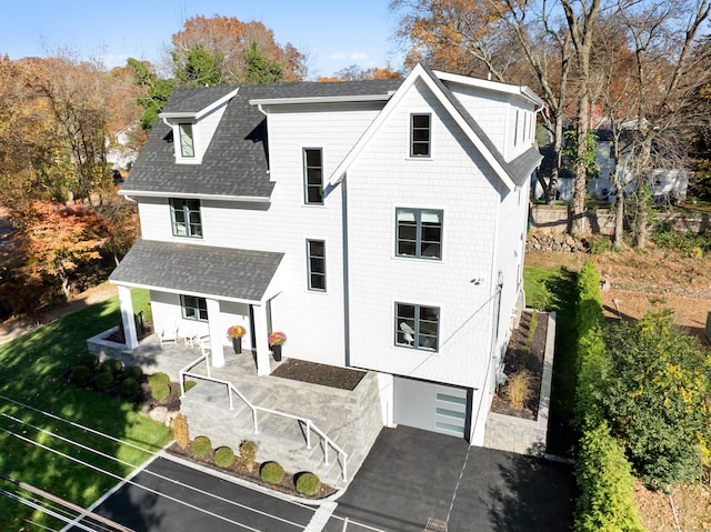 view of front of property featuring a garage, driveway, and a shingled roof