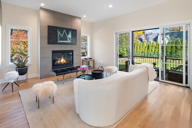 living room with light wood-type flooring, recessed lighting, baseboards, and a tile fireplace