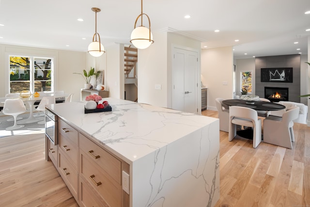 kitchen featuring light wood-style flooring, a fireplace, decorative light fixtures, and recessed lighting