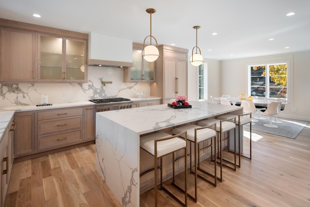 kitchen featuring light wood-style flooring, a breakfast bar, backsplash, and a center island