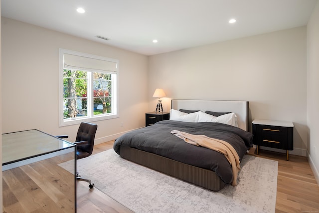 bedroom with baseboards, wood finished floors, visible vents, and recessed lighting