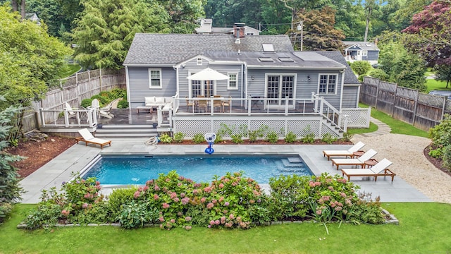 back of property with a fenced backyard, a deck, and a fenced in pool