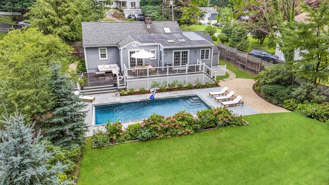 back of property with a fenced in pool, an outdoor hangout area, fence, a deck, and a yard