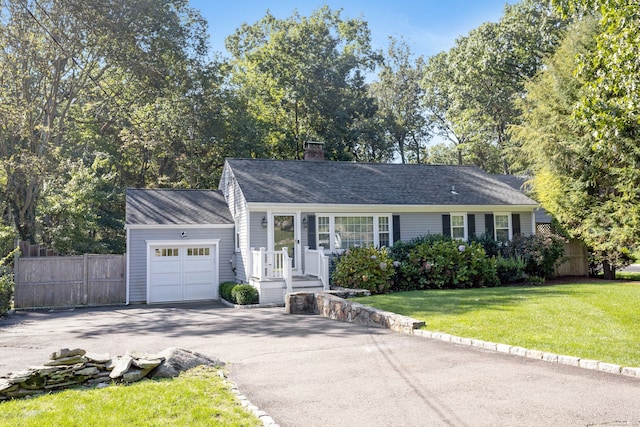 ranch-style home featuring a chimney, a front yard, fence, a garage, and driveway