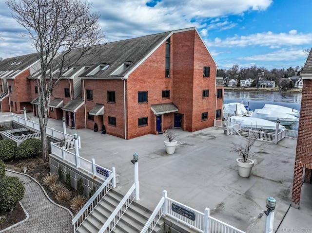 exterior space with stairs, fence, and brick siding