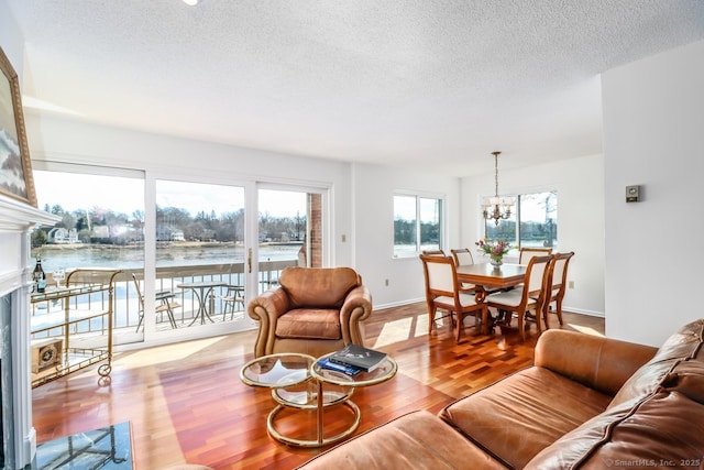 living area with a chandelier, baseboards, a textured ceiling, and wood finished floors