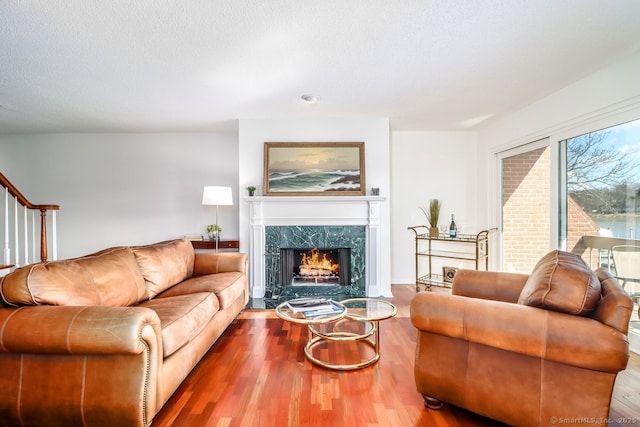 living area featuring a textured ceiling, stairway, wood finished floors, and a premium fireplace