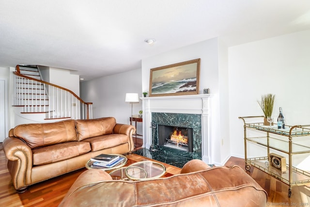 living room featuring stairs, baseboards, wood finished floors, and a high end fireplace