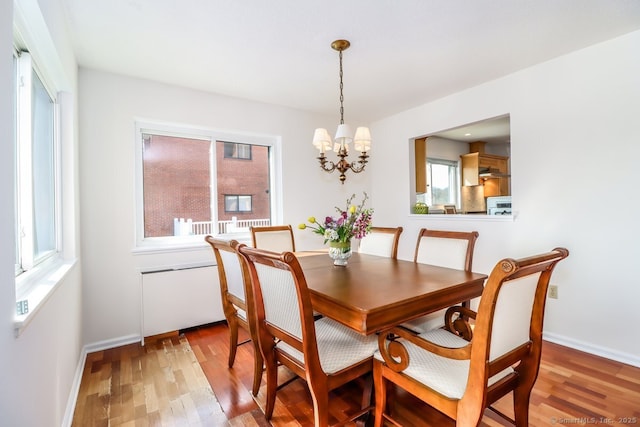 dining room with light wood-style flooring, baseboards, and an inviting chandelier